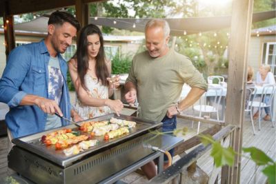 Personne cuisinant autour d'une plancha d'extérieur.